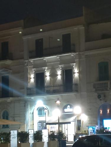 a large white building with a balcony at night at Helios Home in Reggio Calabria
