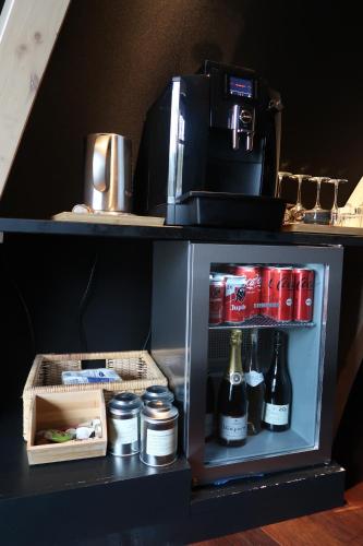 a small refrigerator with drinks and a coffee maker at Room8 luxury glamping in Huldenberg