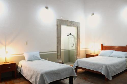 a bedroom with two beds and a mirror on the wall at Hospedaje la gran Tenochtitlán in San Martín Hidalgo