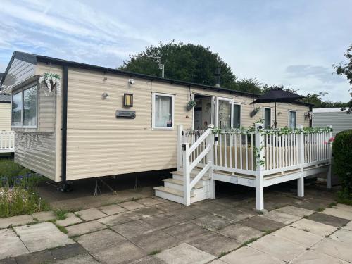 a tiny house with a porch and a fence at KPC-HELLYEAH caravan in Humberston