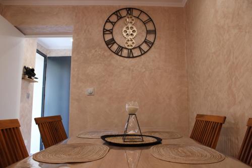 a dining room table with a clock on the wall at Maison privative SPA Jacuzzi Sauna Salle de jeux in Weitbruch