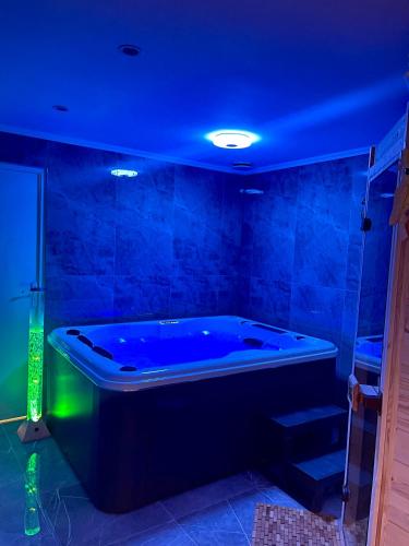 a blue room with a tub with a green light at Maison privative SPA Jacuzzi Sauna Salle de jeux in Weitbruch