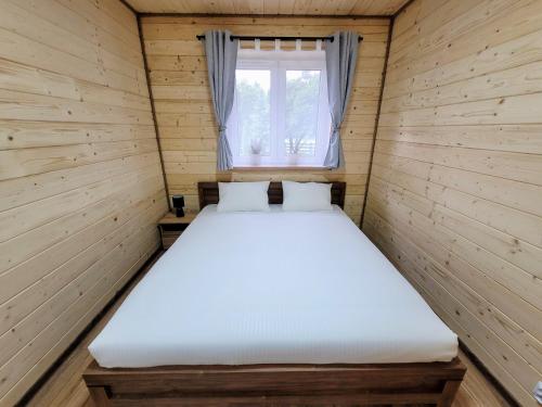 a bed in a small room with a window at Roztoczańska Kryjówka in AdamÃ³w