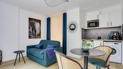 a living room with a blue couch and a table at L'Explorer Rennes Métropole in Betton