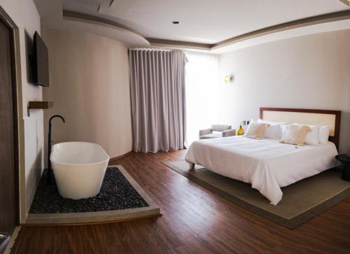 a bedroom with a large bed and a bath tub at Casa Mädi Hotel Boutique in Bernal