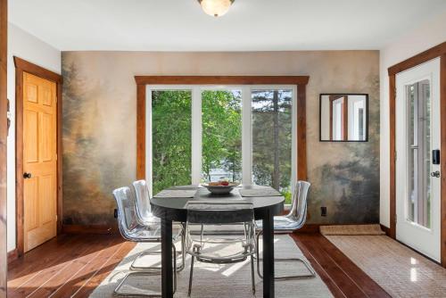 a dining room with a black table and white chairs at Ile privée unique - Islet Chouette in Saint Mathieu Du Parc
