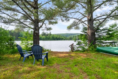 two chairs sitting next to a bench next to a lake at Ile privée unique - Islet Chouette in Saint Mathieu Du Parc