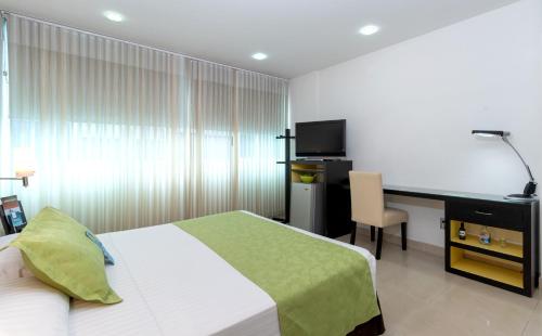 a bedroom with a bed and a desk with a computer at Hotel Chicamocha in Bucaramanga