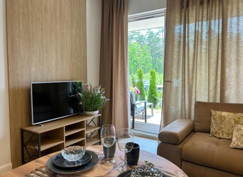 a living room with a television and a table with wine glasses at Augustów apartament nad jeziorem in Augustów