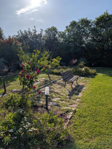 a park bench sitting in a garden with flowers at Casale Elisa Country Hotel in Ladispoli