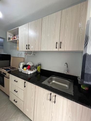 a kitchen with wooden cabinets and a sink at Chic 1BR in the heart of Amaziah in Kinoo