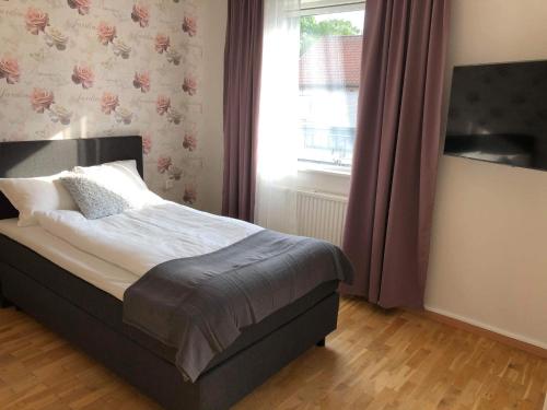 a bedroom with a bed with purple curtains and a window at Smålandsstenar hotell in Smålandsstenar