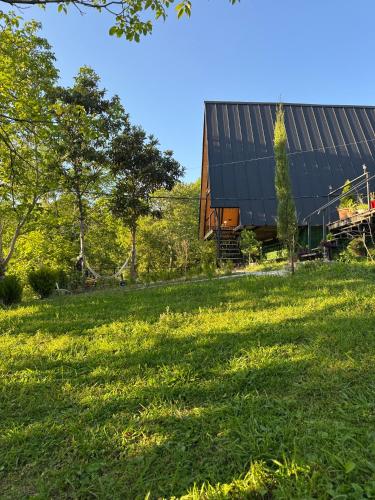 a barn on a grassy field next to a building at Cottage Sataplia in Kutaisi