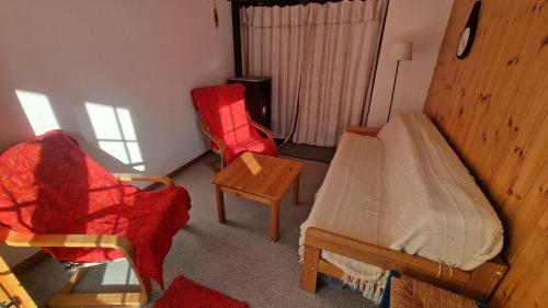 a room with a bed and two chairs and a table at Pra Charris - La Forclaz - Appartement in La Forclaz