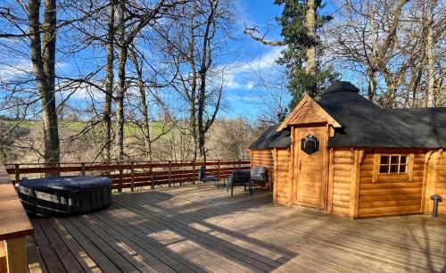 a large wooden cabin on a deck with a grill at Aux Étangs de Jourgnac - Kota in Jourgnac
