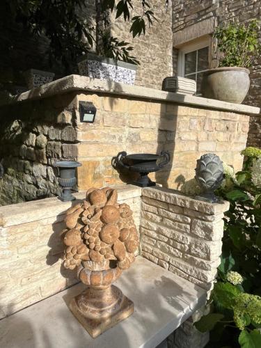 a stone wall with a fire hydrant and a vase with a plant at Chambres d’hôtes de l’Ancienne Auberge in Thaon