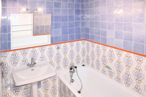 La salle de bains est pourvue de carrelage bleu, d'un lavabo et d'une baignoire. dans l'établissement Résidence Les Carlines - LES CARLINES - Studio 4 Pers. Vue Pistes MAE-6491, aux Orres