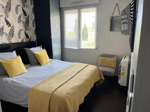 une chambre avec un lit avec des oreillers jaunes et une fenêtre dans l'établissement Apartment in park with pool, à Cannes