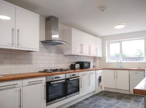 a kitchen with white cabinets and a stove top oven at City breaks Corby Double ensuites in Rockingham