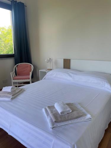 a white bed with towels on it with a chair at Villa Andrea in Rodello