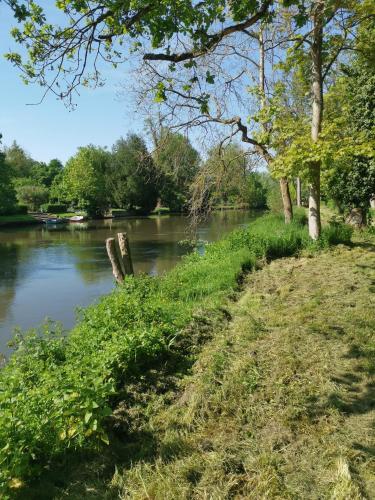 a river with trees and grass next to a body of water at Mobilhomes 6 & 4 pers à Ivry La Bataille Clim TV Wifi terrasse & confort Paris Eure Gestion in Ivry-la-Bataille