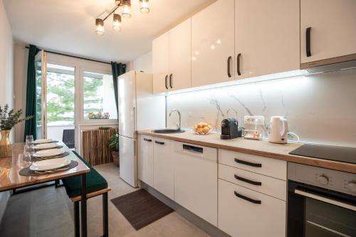 a kitchen with white cabinets and a wooden table at Sarajevo Midway Premium Brand New Apartment in Sarajevo