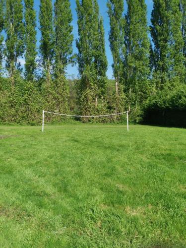 a net in a field of grass with trees at Mobilhomes 6 & 4 pers à Ivry La Bataille Clim TV Wifi terrasse & confort Paris Eure Gestion in Ivry-la-Bataille