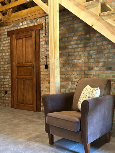 a brown chair sitting in front of a brick wall at Mazurska Zagroda - Żabi Rechot - dom - stodoła - jacuzi-sauna in Worliny