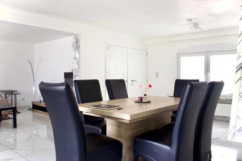 a dining room with a wooden table and black chairs at Chez Nadège in Affligem