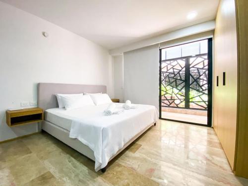 a bedroom with a large white bed and a window at Downtown Playa Studio with Rooftop Pool Steps to Everything in Playa del Carmen