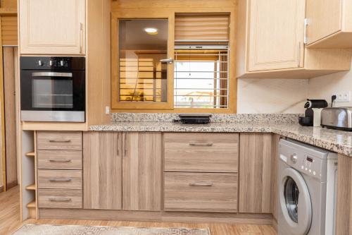 a kitchen with wooden cabinets and a washer and dryer at Peaceful Family Villa on a Farm with Private Pool and Stunning Mountain Views in Agadir