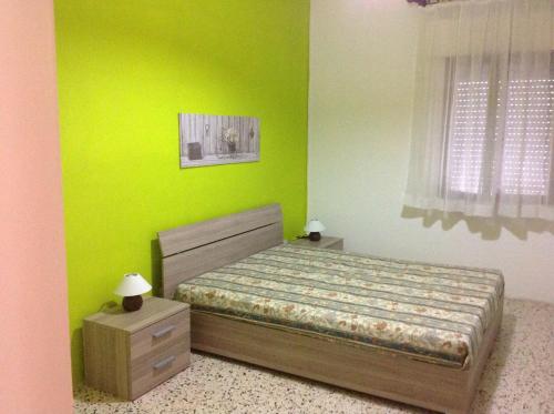 a green bedroom with a bed and two night stands at Casa Alieta in Torre Lapillo