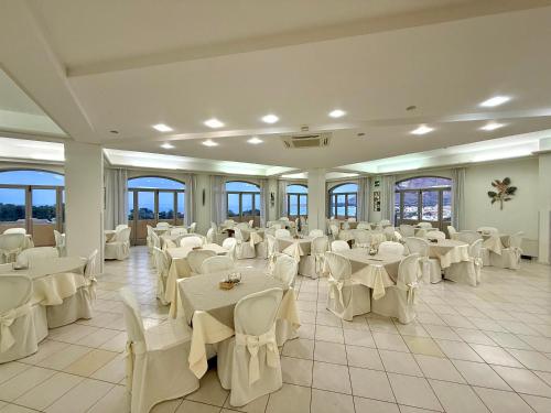 a banquet hall with white tables and white chairs at Hotel Panoramic in San Vito lo Capo