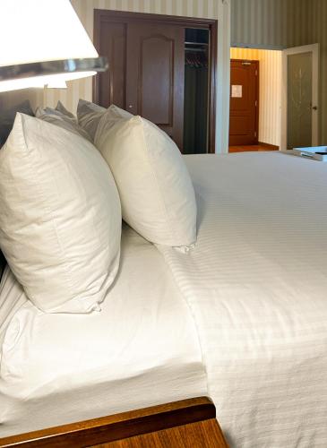 a white bed with pillows on top of it at Prestige Prince George Lodge in Prince George