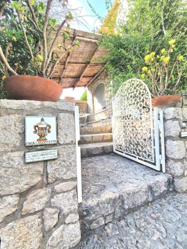 ein Tor in einer Steinmauer mit einem Schild und Pflanzen in der Unterkunft Casa Laboccetta in Capri