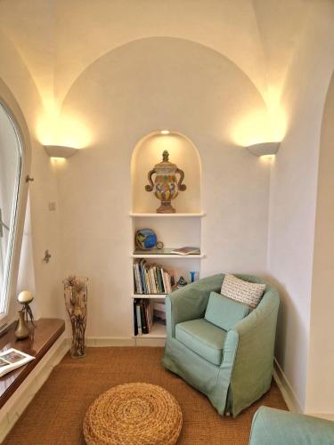 ein Wohnzimmer mit einem Sessel und einem Bücherregal in der Unterkunft Casa Laboccetta in Capri