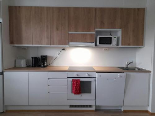 a kitchen with white cabinets and a microwave at Convenient Apartment for 3 in Oulu
