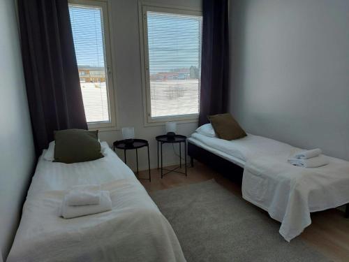 two beds in a room with two windows at Spacious Apartment for 5 with Sauna in Oulu