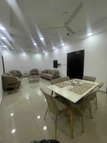 a living room with a table and chairs and a screen at Spacious 2 bedroom & maid room in Jazīrat Umm ash Shajar