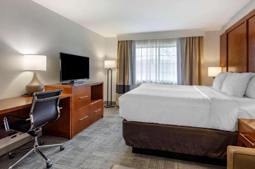 a hotel room with a bed and a desk and a television at Comfort Suites Golden West on Evergreen Parkway in Evergreen