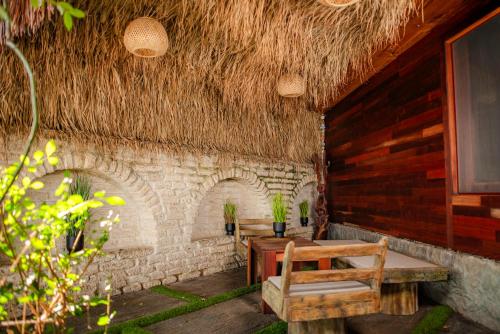 a patio with a table and chairs and a straw roof at Cossara luxury villas - Adults Only in Balchik