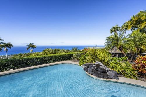 a swimming pool with the ocean in the background at Hale Aikane in Kailua-Kona