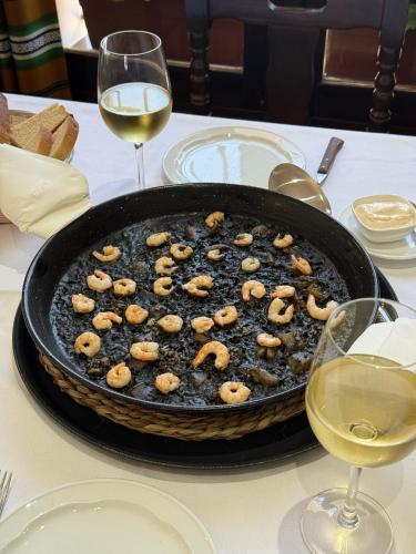 a pan of food on a table with two glasses of wine at El Mirador del Valle in San Jose del Valle