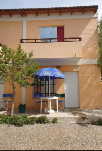 a table with an umbrella in front of a house at Las Grutas Suites in Las Grutas