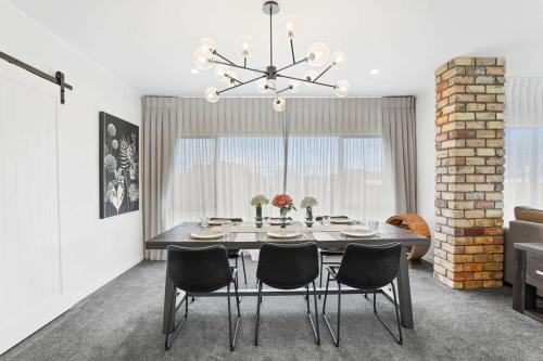 a dining room with a table with chairs and a chandelier at Airport Oasis in Rotorua
