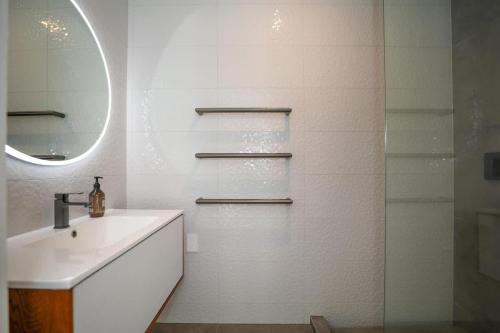 a white bathroom with a sink and a mirror at Airport Oasis in Rotorua