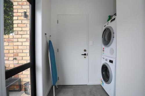 a laundry room with a washing machine and a door at Airport Oasis in Rotorua