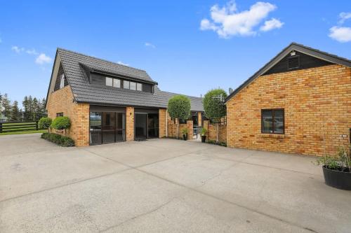 a brick house with a large driveway at Airport Oasis in Rotorua
