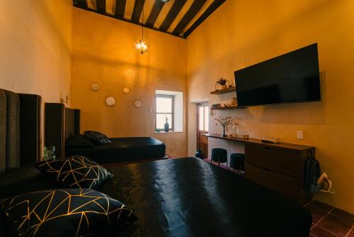 a living room with a bed and a flat screen tv at Hotel Boutique Casa Lanz XVII in Campeche