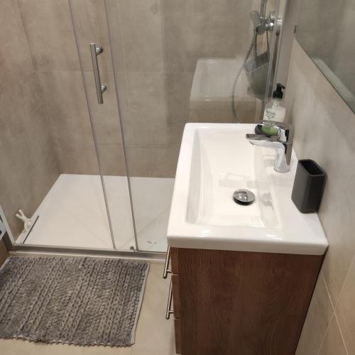 La salle de bains est pourvue d'une douche et d'un lavabo blanc. dans l'établissement Magnifique appartement centre ville, à Hyères